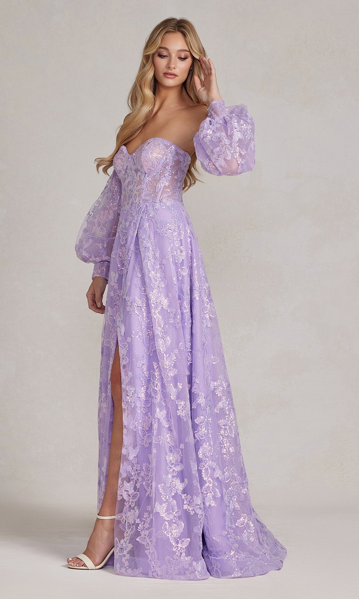 A woman models the Long Puff-Sleeve Prom Dress with Sheer Bodice, a lavender gown with removable long sleeves, high slit, and floral embroidery, standing against a plain light background.